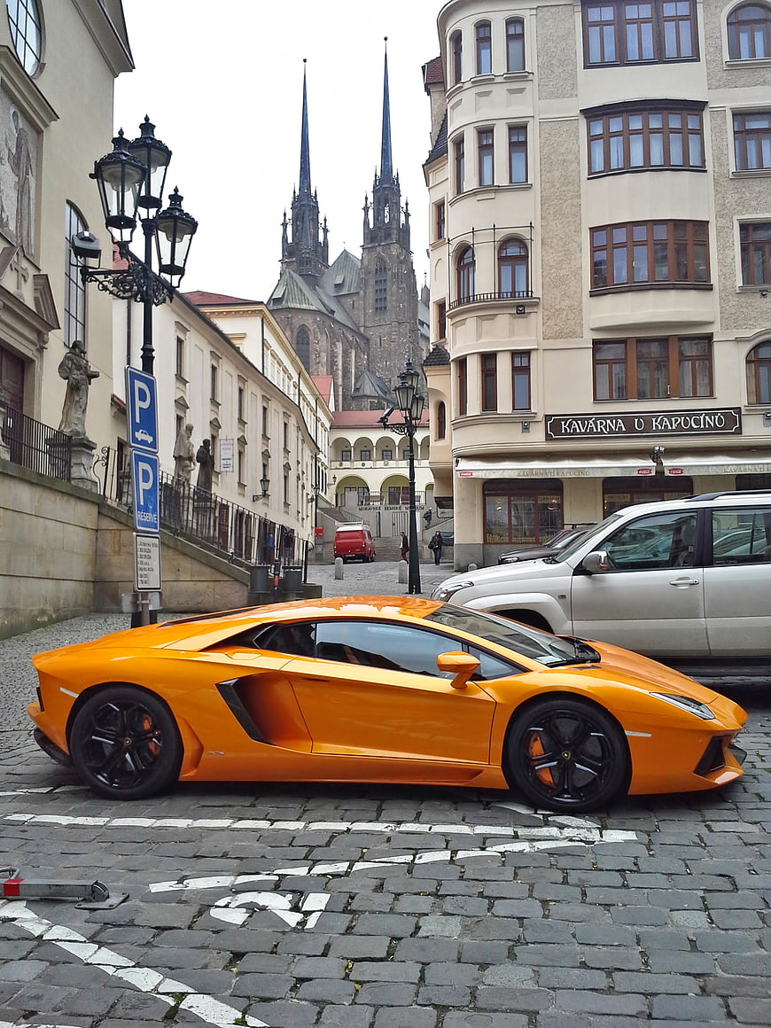 Orange Lamborghini Aventador parked on cobblestone street in Brno