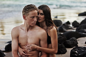 Romantic couple embracing on a rocky beach with ocean waves