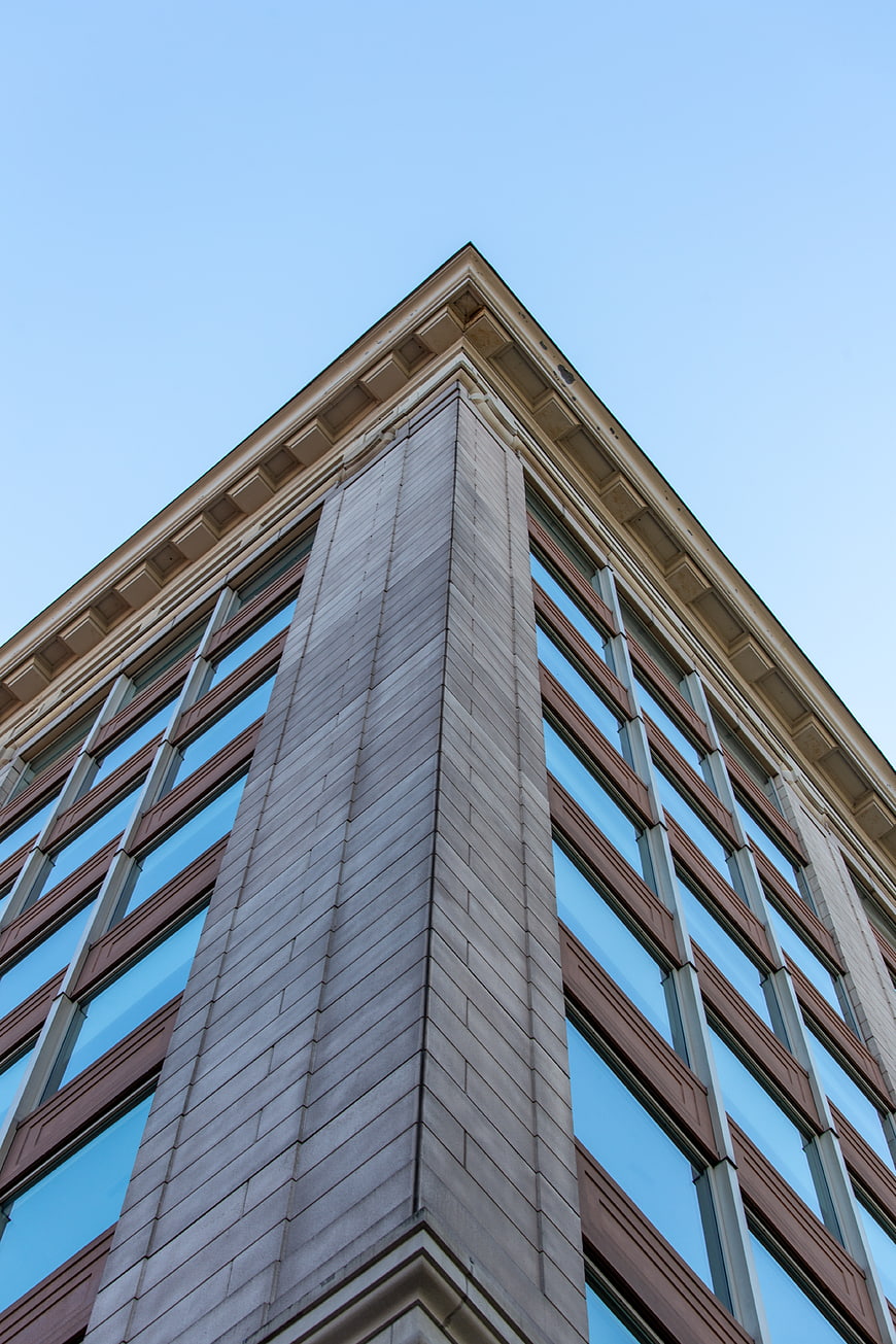 Low angle view of modern office building corner against blue sky