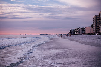 Serene Beach at Dusk with Hotels and Walking People