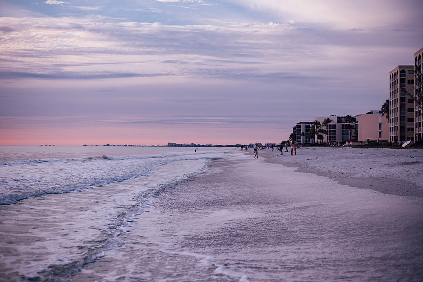 Serene Beach at Dusk with Hotels and Walking People