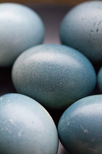Close-up of blue speckled eggs in a rustic wooden basket