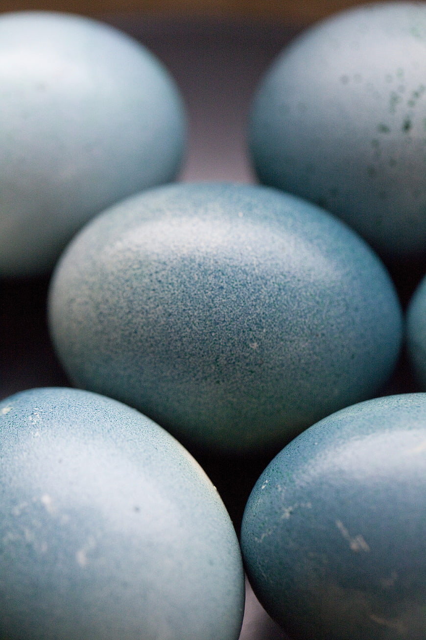Close-up of blue speckled eggs in a rustic wooden basket