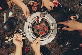Top-Down View of Friends Grilling Meat at a Table