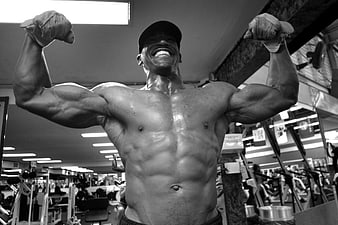 Muscular Bodybuilder Flexing Biceps In Black And White Gym
