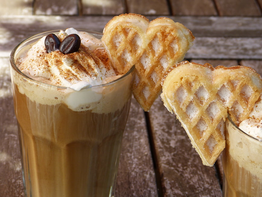 Heart-shaped waffle with iced coffee and whipped cream