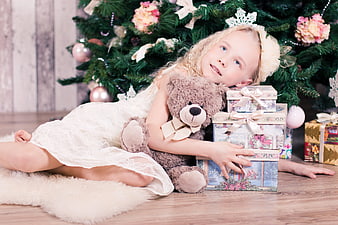 Cute Girl with Teddy Bear and Gifts by Christmas Tree