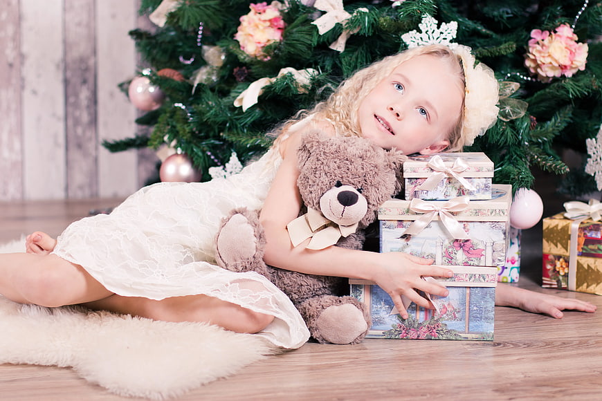 Cute Girl with Teddy Bear and Gifts by Christmas Tree