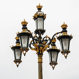 Ornate Black and Gold Street Lamp Against White Sky