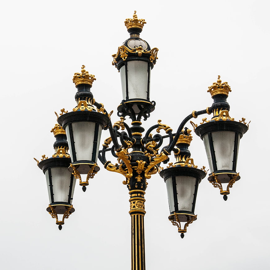 Ornate Black and Gold Street Lamp Against White Sky