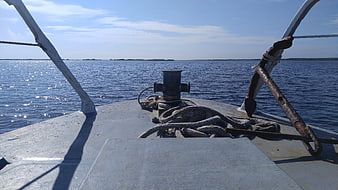 Bow of a boat with anchor and rope on calm blue sea