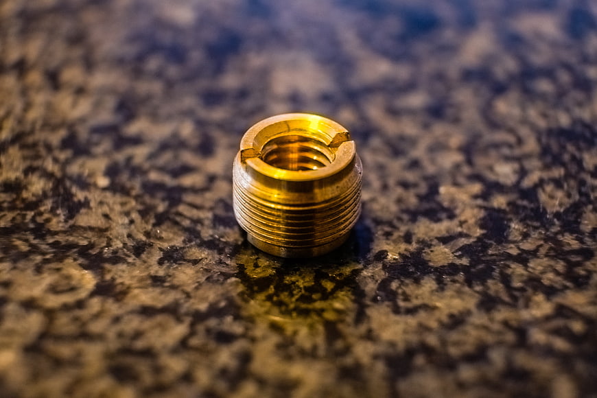 Close-up of a brass threaded fitting on a textured surface