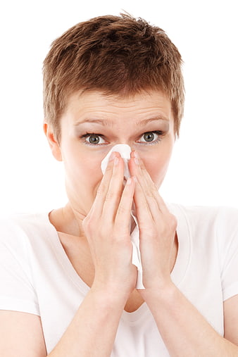 Woman with short hair blowing nose with tissue