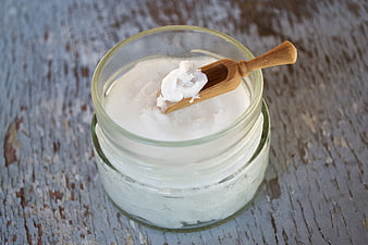 Coconut Oil in Glass Jar with Wooden Scoop on Rustic Wood