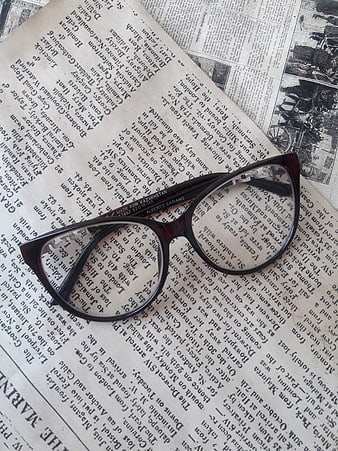 Vintage eyeglasses resting on old newspaper pages with printed text