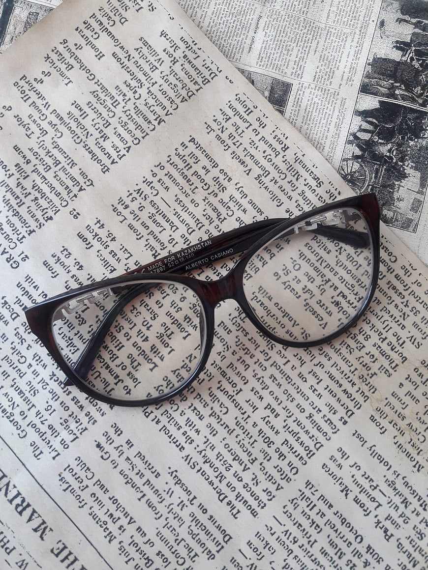 Vintage eyeglasses resting on old newspaper pages with printed text