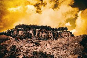 Dramatic Golden Sky Over Rocky Cliff with Forest