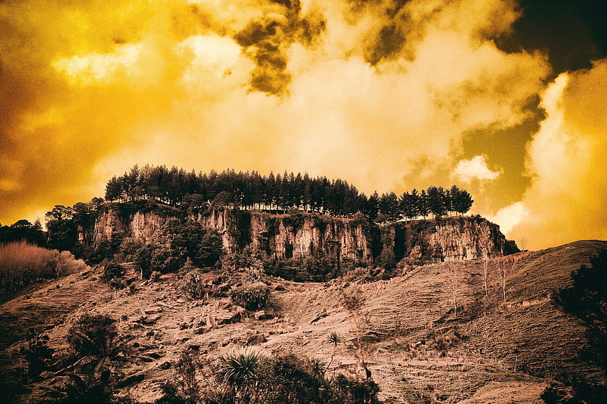 Dramatic Golden Sky Over Rocky Cliff with Forest