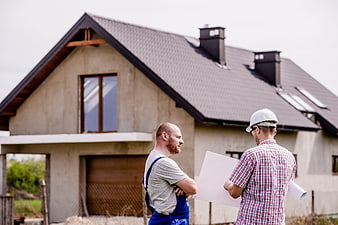 Architect and Builder Discussing Plans at House Construction Site