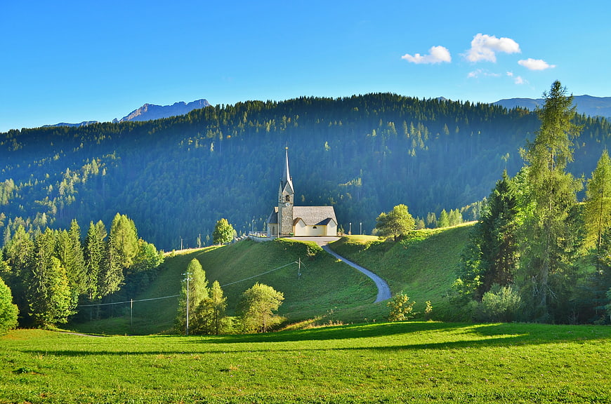 Scenic Church on Green Hilltop with Forest and Mountains