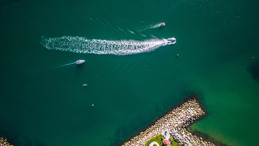 Aerial view of speedboats creating white wakes on deep green water