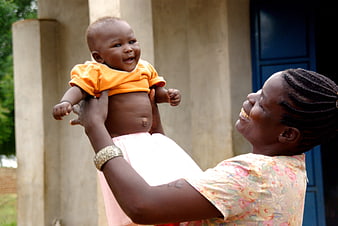 Happy African Mother Holding Smiling Baby Outdoors