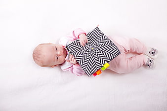 Baby Girl Lying Down Holding Black and White Patterned Sensory Book