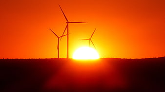 Silhouette of Wind Turbines Against Vibrant Orange Sunset