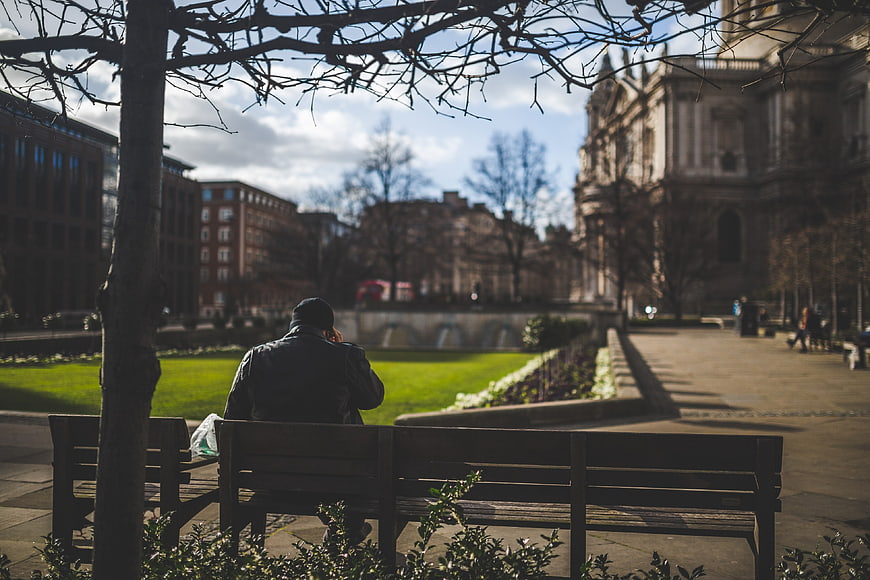 Man sitting alone on park bench in London
