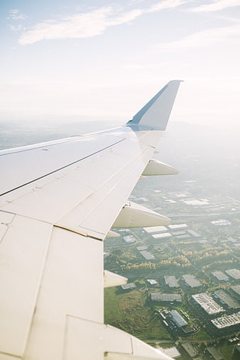 Airplane wing view over suburban landscape during flight