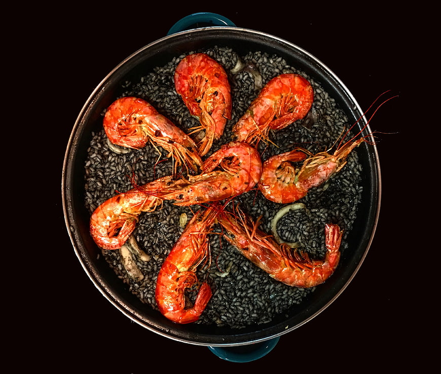 Overhead View of Black Rice Paella with Shrimp in a Dark Pot