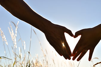 Couple Hands Forming Heart Shape Silhouette Against Sunset Sky