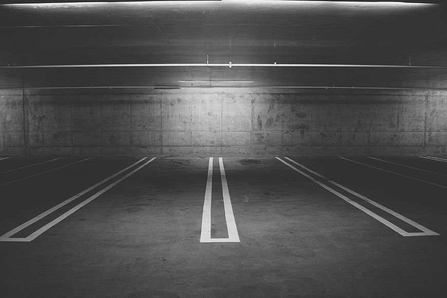Empty underground parking garage with concrete walls and white lines