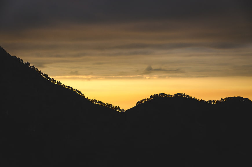 Silhouette of Mountain Ridges Against Golden Sunset Sky