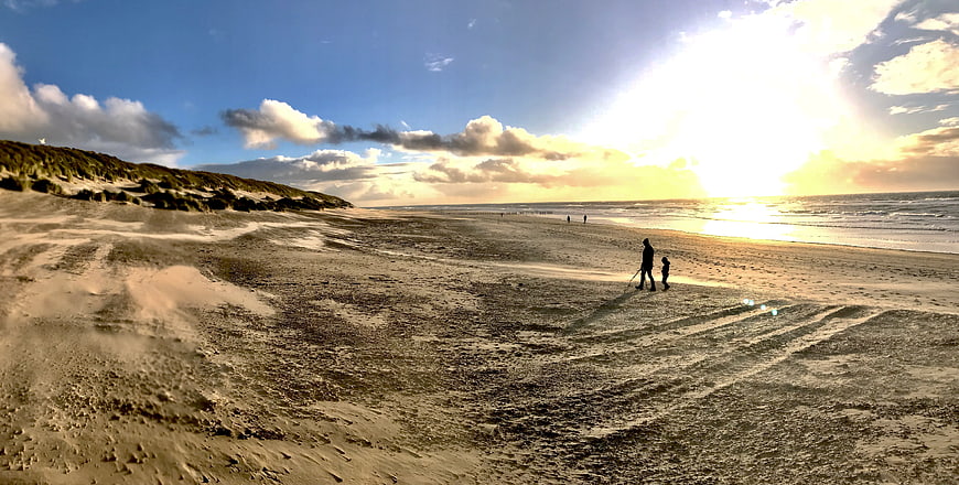 Silhouette of Parent and Child Walking on Sandy Beach at Sunset