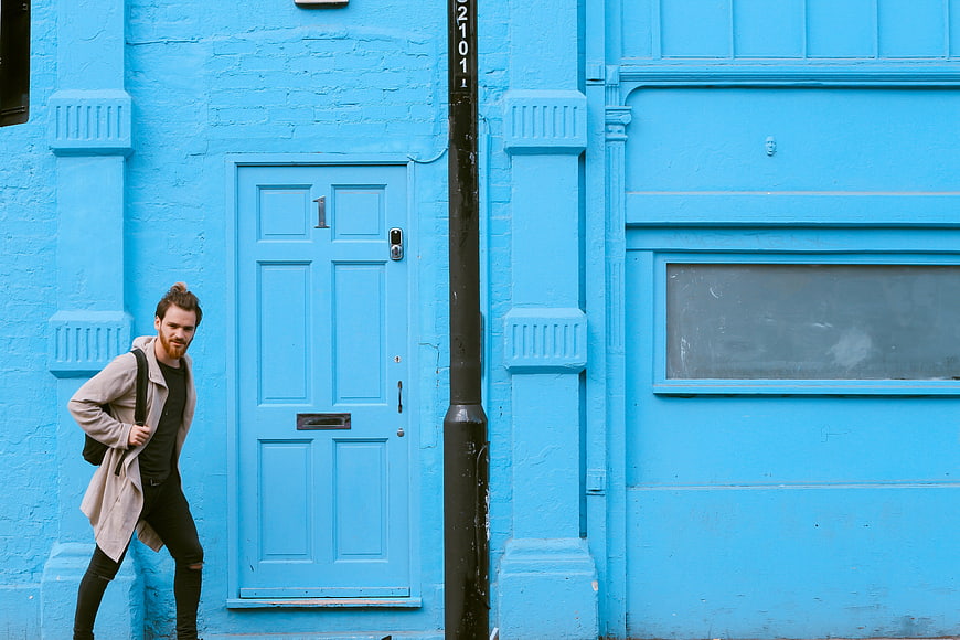 Man walking past vibrant blue building facade
