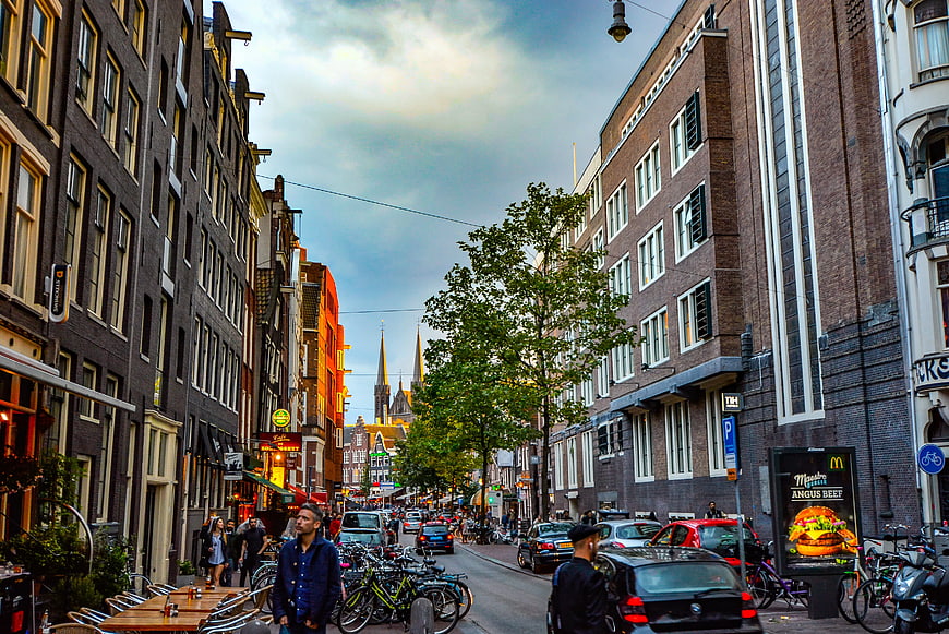 Busy Amsterdam Street Scene with Bicycles and Church Spires