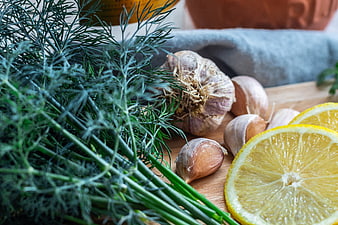 Fresh garlic, dill, and lemon slices on wooden board