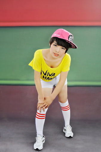 Young woman in yellow t-shirt and pink cap posing on tennis court