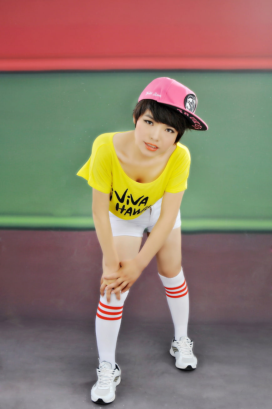 Young woman in yellow t-shirt and pink cap posing on tennis court