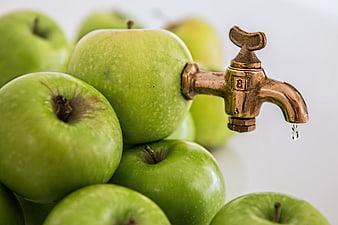 Green apples with brass tap dripping water