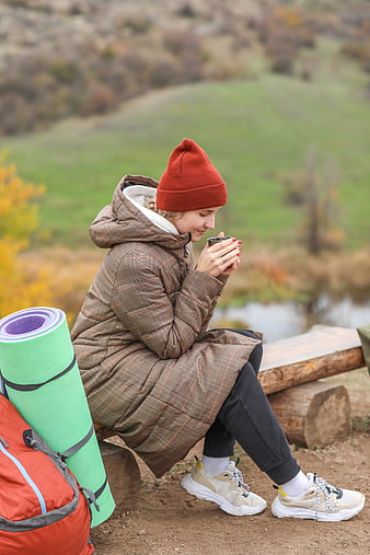 Woman hiking in autumn drinking coffee outdoors