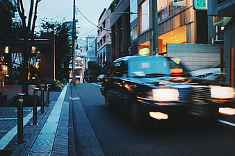 Motion Blur Black Taxi Driving on City Street at Dusk