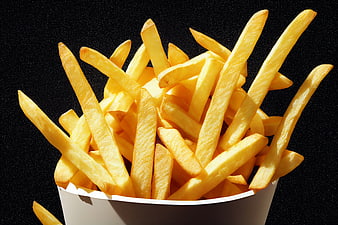 Golden French Fries in White Paper Container on Black Background