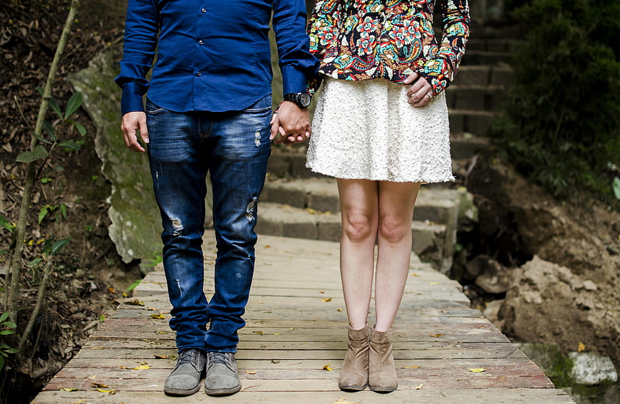 Couple Holding Hands on Wooden Bridge in Nature