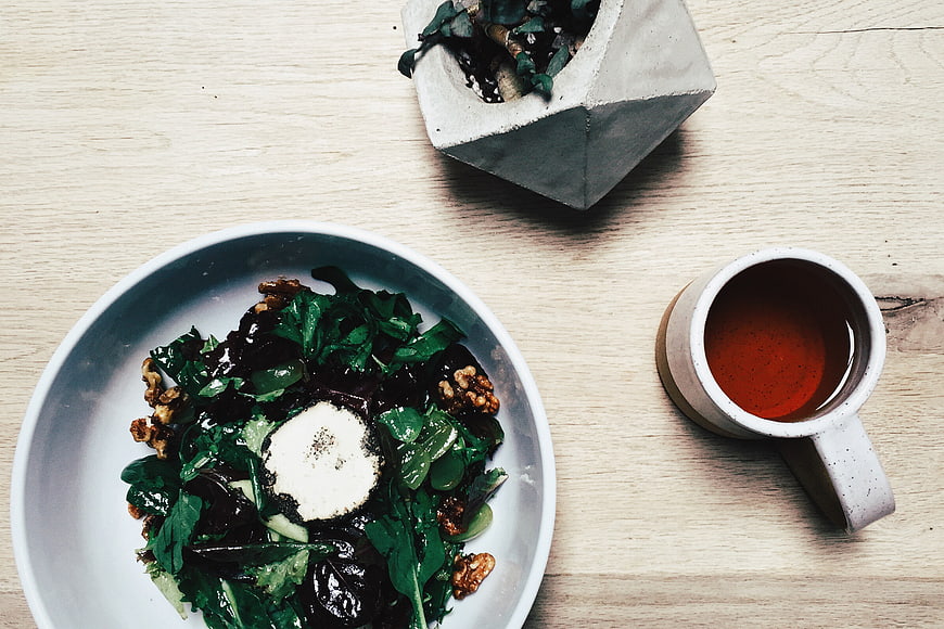 Overhead view of healthy salad bowl with tea on wooden table