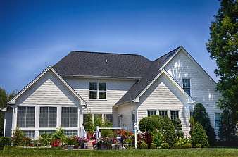 White suburban house with garden and blue sky