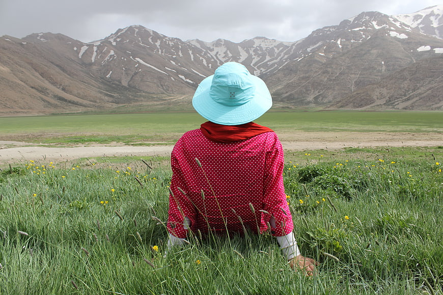 Woman in Red Polka Dot Shirt Sitting in Mountain Meadow
