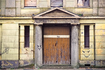 Abandoned building facade with boarded windows and graffiti