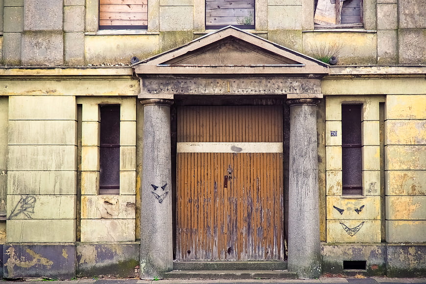 Abandoned building facade with boarded windows and graffiti